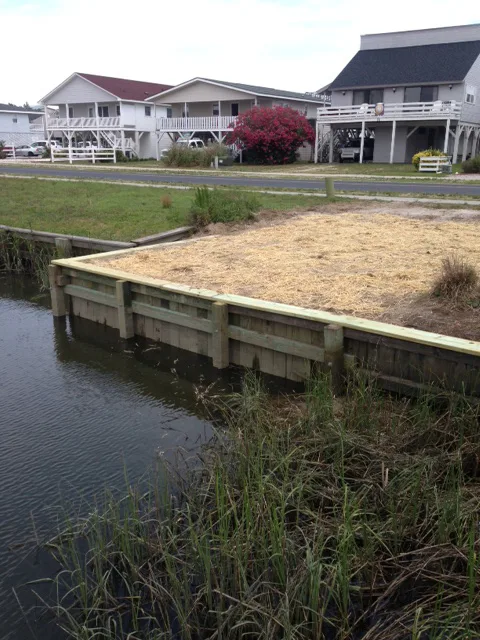 A completed wood bulkhead with fresh backfill along a canal shoreline