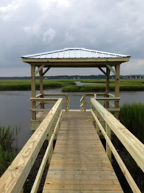 A covered dock with a standing-seam metal roof over a marsh creek