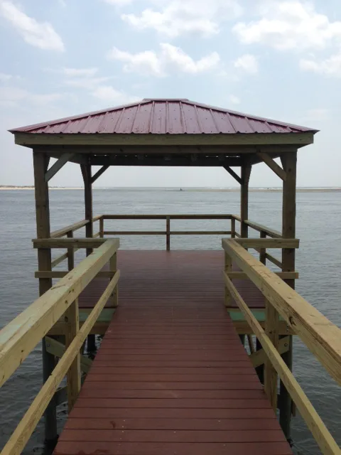 A covered dock with a hip roof extending over open coastal water