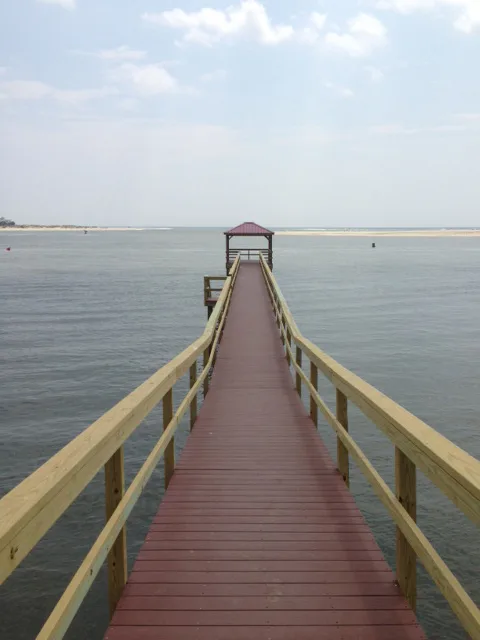 A walkway leading to a covered dock at the edge of a tidal channel