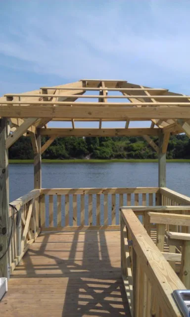 The timber roof framing of a covered dock under construction over the water