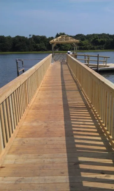A long railed walkway ending at a covered platform over the water