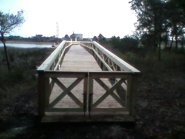 The end of a wooden pier finished with X-braced railings over the marsh