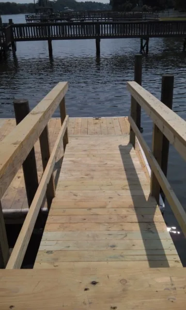 A railed wooden pier walkway leading out to deeper water